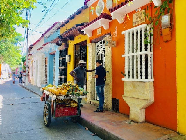 two men talking in front of brightly colored buildings, best places to visit in Colombia, cartagena, colombia, colombia destinations, cartagena turismo, tour cartagena, Cartagena de indias playas