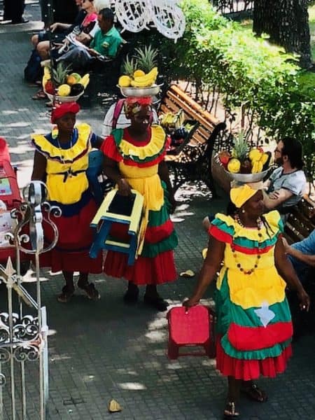 beautiful women wearing red, green, and yellow dresses with fruit on their heads, cartagena, colombia, colombia destinations, cartagena turismo, tour cartagena, Cartagena de indias playas, palenque, palenque san basilio, unesco, unesco world heritage site