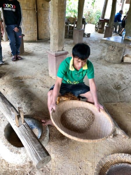 what to do in luang prabang, things to do in luang prabang, living land, young man filtering rice