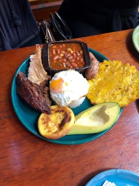 bandeja paisa, things to eat in colombia, colombia travel tips plate of food with chicken, beans, avocado, corn cake
