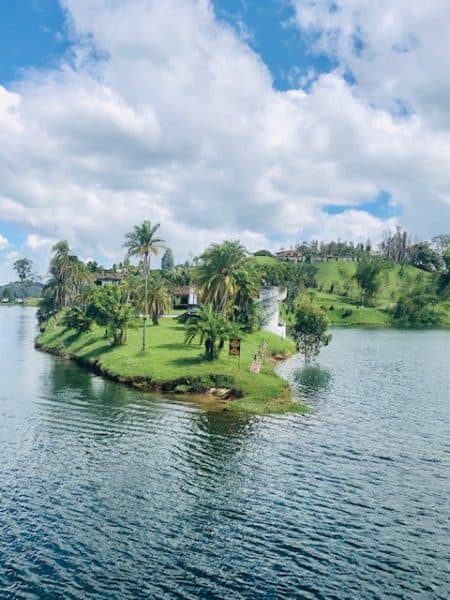 medellin, things to do in medellin, Guatapé, Guatape colombia, day trips from medellin, guatape, places to visit in colombia, colombia tourist attractions, day trips from medellin, man from medellin, pablo escobar, colombia travel tips, beautiful green area looking out over a lake