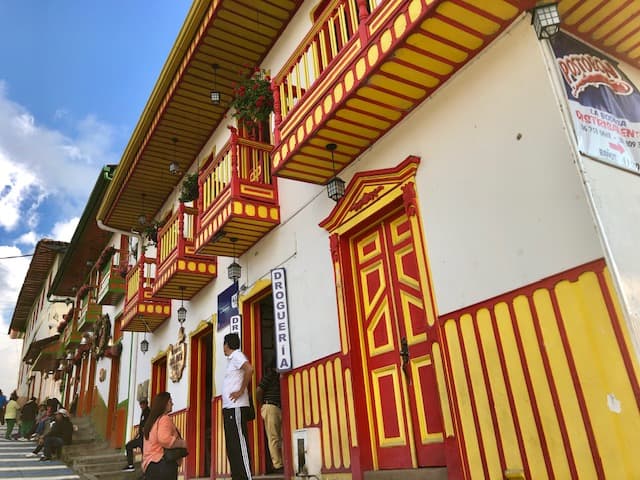 salento colombia, things to do in salento, salento quindio, things to do in salento colombia, what to do in salento colombia, places to visit in colombia, brightly colored building with two people talking in fromt