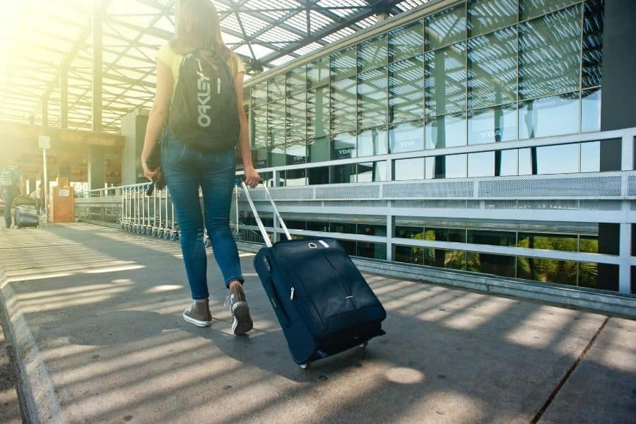 woman wheeling luggage, woman and a carry on bag entering the airport, travel hacks, travel smarter, travel accessories, easy travel, easier travel