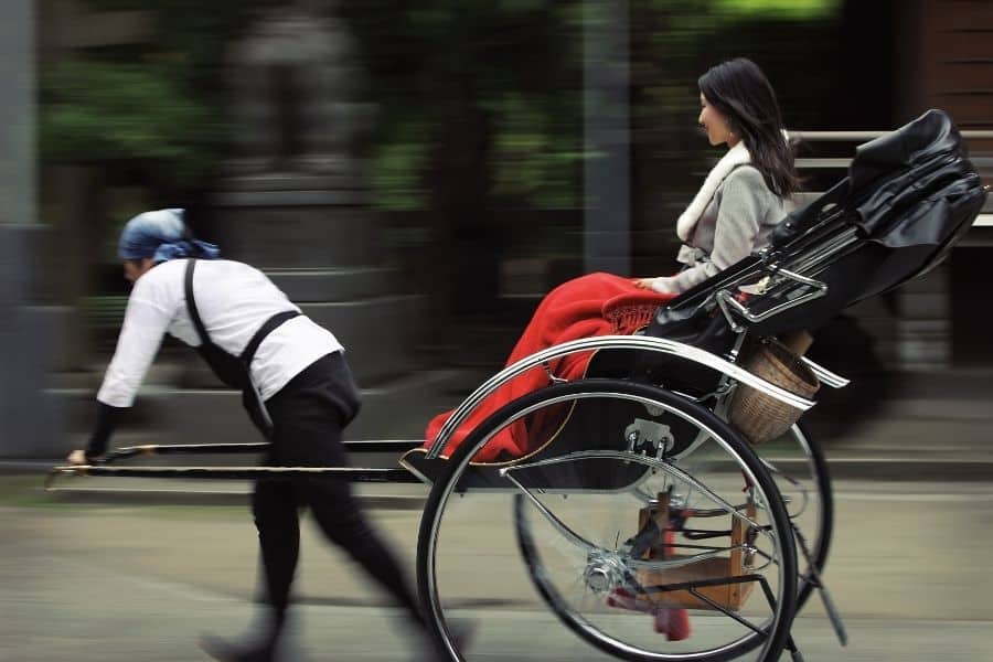 man pulling a rickshaw with a woman in it, rickshaw in tokyo