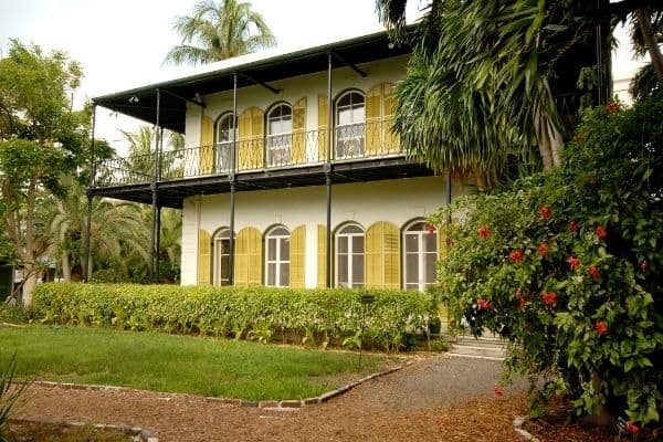 things to do in dry tortugas, ernest hemingway house, white house with yellow shutters, big trees in the front yard