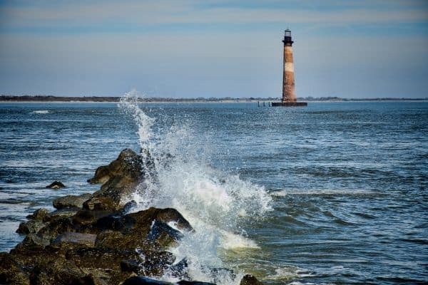 Morris island shore, lighthouse in distance, waves crashing over rocks, places to visit in charleston
