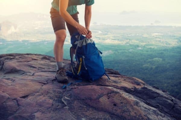 woman tying her daypack, hiking gear list for beginners, best hiking gear for beginners