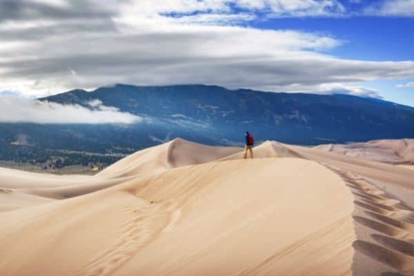 man standing on top of the dunes, camping in great sand dunes, best time to visit great sand dunes national park, great sand dunes lodge