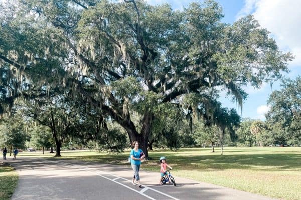 live oaks at audobon park, child on bike, mom walking next to child on bike