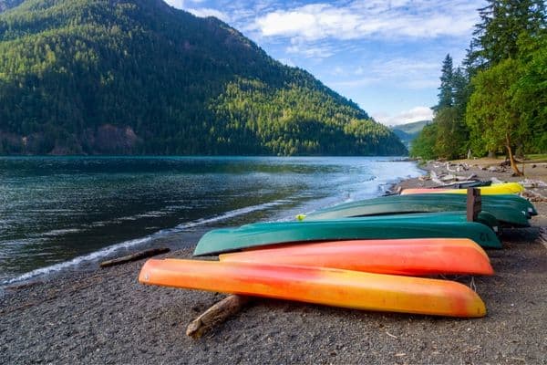 canoes on the shore of lake crescent, tree lined mountains in the distance, lake crescent washington