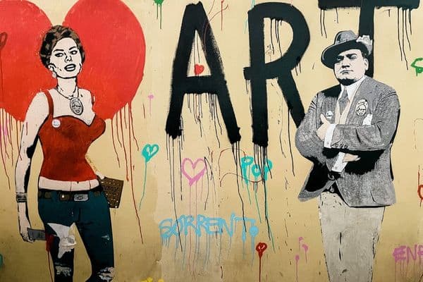 mural wall in sorrento, man wearing suit, woman in red tank top and blue jeans, the word art in big bold letters, paintings of hearts 