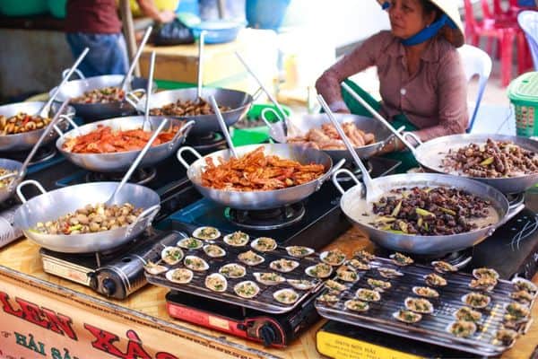 street food tour, woman selling street good, big woks on hot plates, things to do in saigon, 
