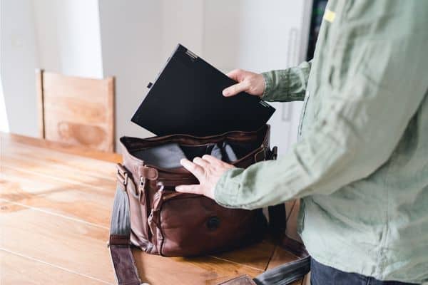 man putting laptop into bag, laptop sleeve, laptop compartment, personal item bag for flying
