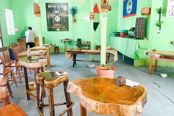 inside of AJAW chocolate building, green painted walls, tables and chairs for the tour, belize chocolate tours