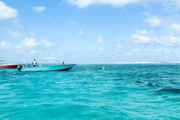 turqouise water, blue water with sunny skies, boat floating in the water, san pedro belize 