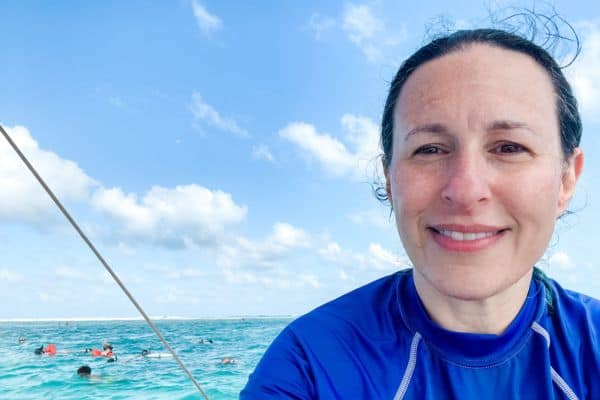me smiling on the boat with the water and snorkelers behind me 