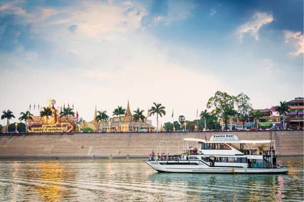 sunset cruise on the riverfront district, palm trees and temples in the distance, accommodation in phnom penh, phnom penh hotel, riverfront district