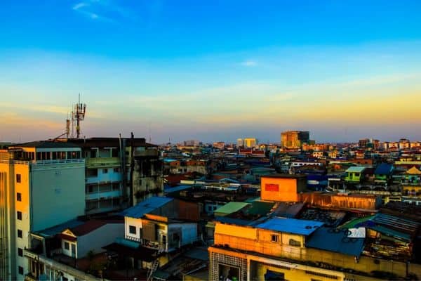 sunrise over phnom penh, blue and yellow sky, buildings rising in the distance, best hotels in phnom penh, phnom penh neighborhoods
