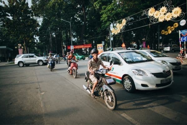 men on motorbikes in a quiet street of saigon, white cars driving by
