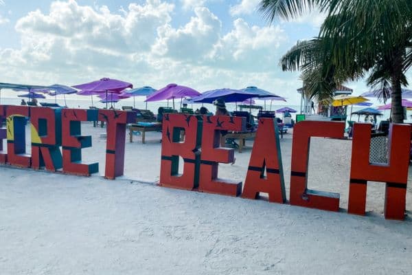 big red secret beach letters in the sand, purple umbrellas and chairs in the background, search beach ambergris caye, secret beach san pedro