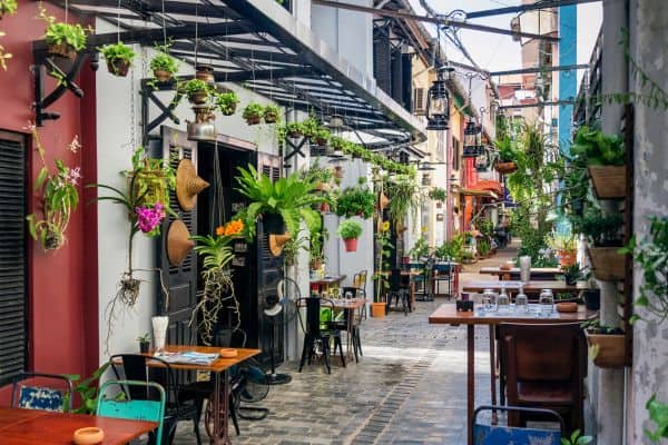 old french quarter, small alleyway with restaurants, potted plants hanging from terraces, tables for restaurants sitting outside
