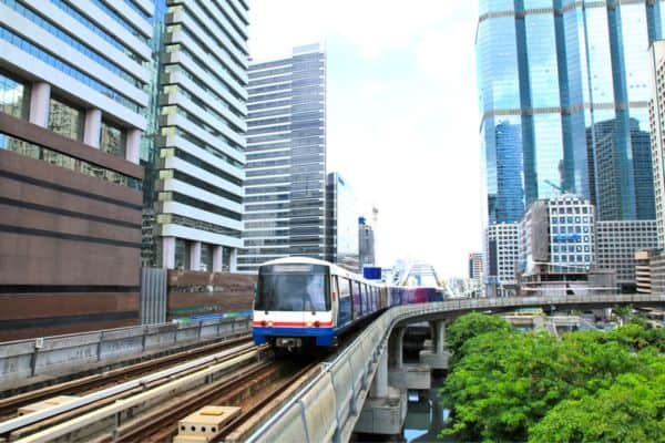 how to get around bangkok, skytrain going down the rails between business buildings 