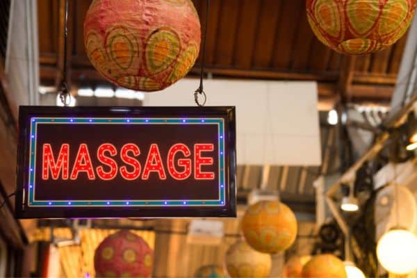 red neon sign advertising a thai massage