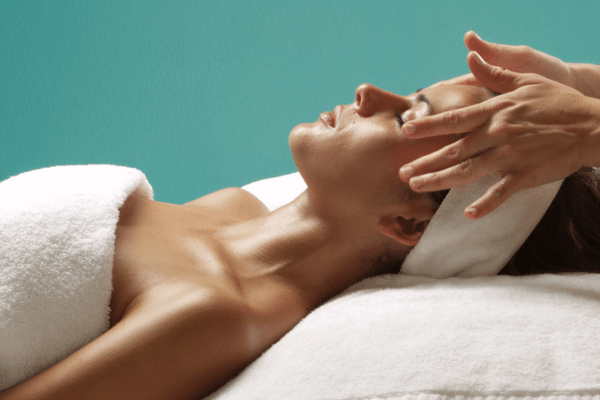 woman laying on massage table with someone rubbing her temples