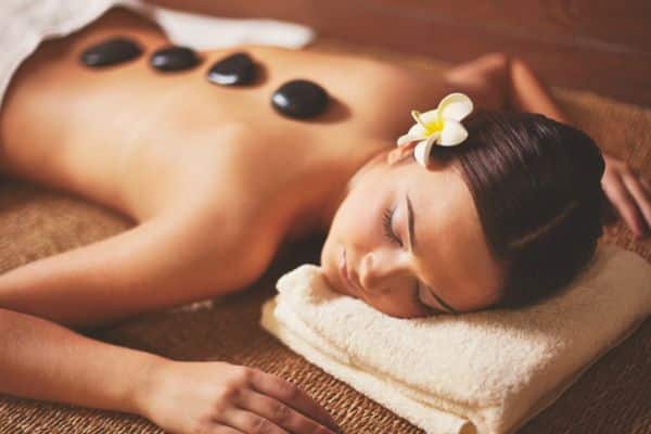 woman laying on massage table with hot stones in the center of her back, couples massage deals dublin, couples spa packages dublin