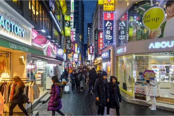 busy street of myeongdong, people in winter jackets shopping, lit up store fronts advertising clothes, where to stay in seoul, seoul accommodation