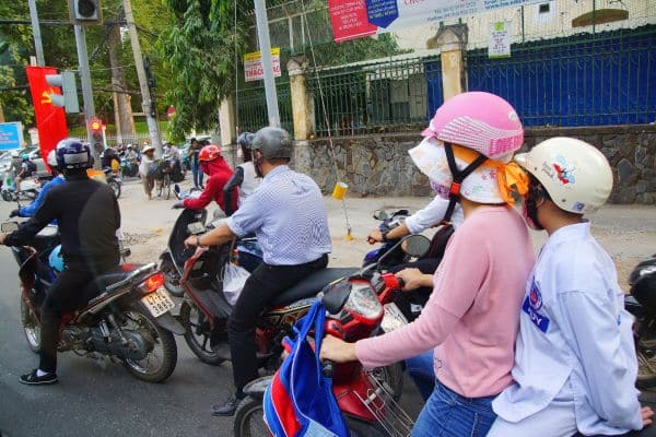 people riding motorbikes through traffic, woman driving motorbike with child on the back, how to get around ho chi minh city