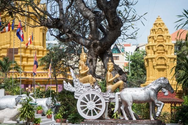 two golden monuments with a horse and silver carriage out front, buddhist statues sitting in the carriage, wat phnom, phnom penh day tour