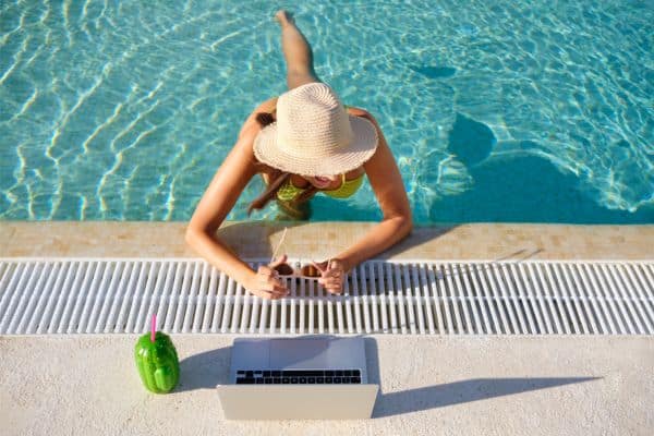 woman in pool with a computer sitting near the pool, how to start a side hustle, work from home side hustles 