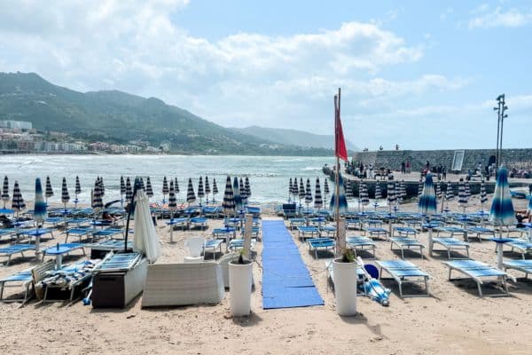 cefalu beach, spiaggia di cefalu, best beaches in cefalu, beaches in cefalu, chairs and umbrellas on the sand, beach water and mountains in the distance
