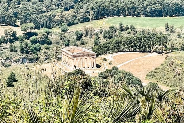 aeriel view of the segesta temple in the middle of beautiful fields of grass and trees