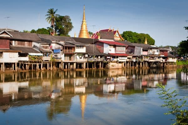 chanthabook waterfront, houses on stilts lining the river, top of golden temple in the background, bangkok day trips, day trips from bangkok