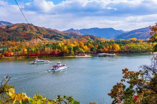 nami island coast, leaves changing color for the fall, boats in the water, mountains in the distance, seoul day trips, day trips from seoul
