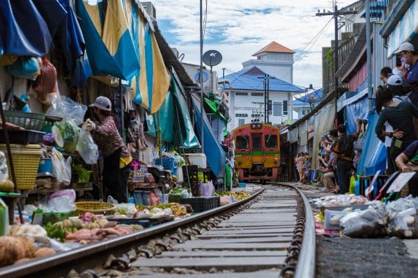 maeklong railway market, vendors on both sides of the track, train coming through on the tracks, bangkok day trips, bangkok day tours, best weekend day trips from bangkok