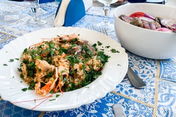 seafood risotto, sicilian salad, seafood risotto and sicilian salad on a blue and white tablecloth