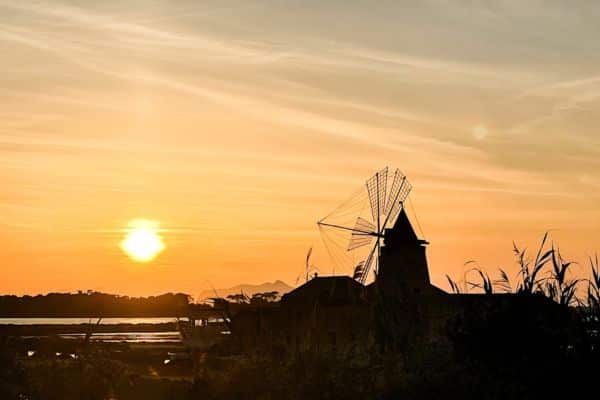 amazing sunset going down over the windmill at marsala salt pans