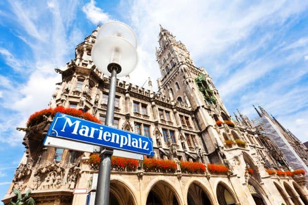 up close view of the marienplatz sign on a lampost, architecture building in the background