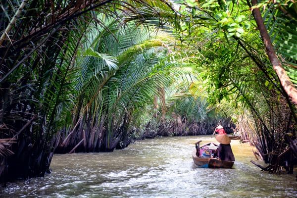 woman sitting on a small boat sailing through the mekong delta, day trip from ho chi minh