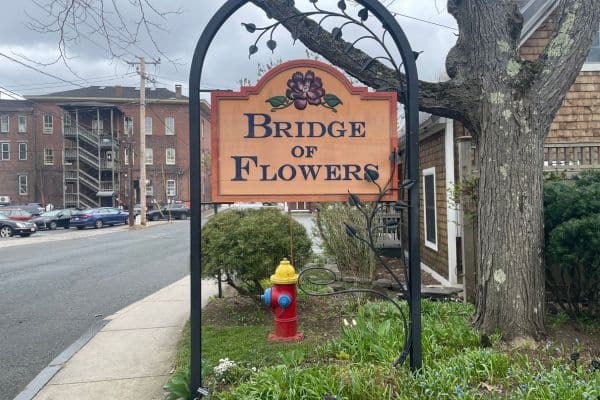 sign for bridge of flowers, buildings in the background with cars in a parking lot, things to do in western massachusetts, towns in western massachusetts, day trips in massachusetts