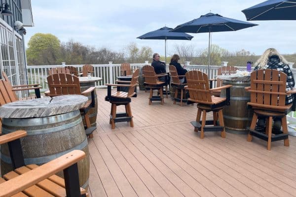 outside of the winery, wine barrels used as tables, chairs and umbrellas with people sitting, 