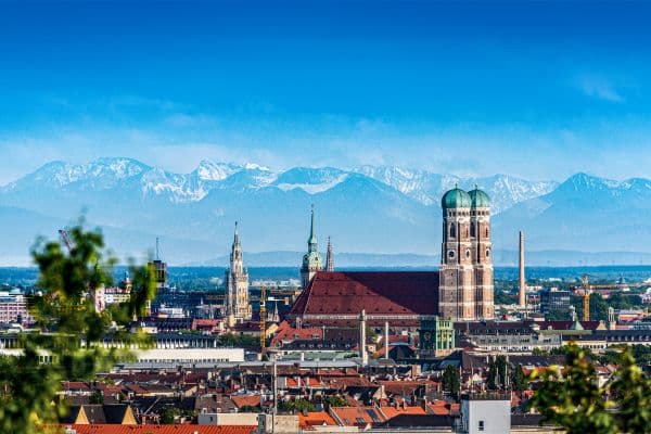 city of munich, bavarian alps with snow on them in the back, munich cathedral standing tall in the background