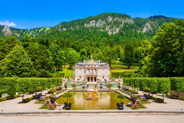 linderhof palace, green hills and mountains in the background, pond in front of the palace with landscaping around it, weekend trips from munich, munich day trips, 