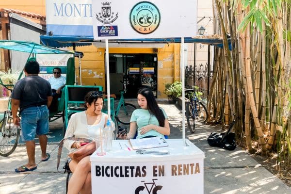 two salespeople sitting behind a desk where you can rent bikes, living in merida mexico, places to see in merida