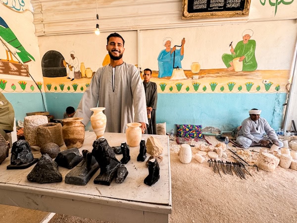 local artist smiling behind his ceramics and vases that he made 