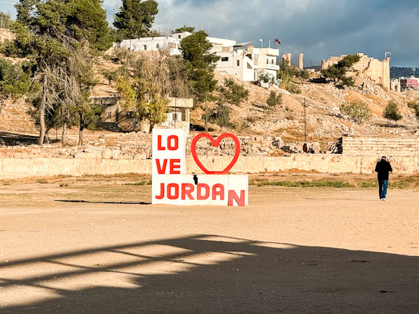 small love jordan sign with a local man walking by, trees and local buildings in the background, g adventures jordan